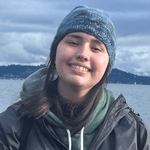 A person facing forward and smiling in front of Puget Sound