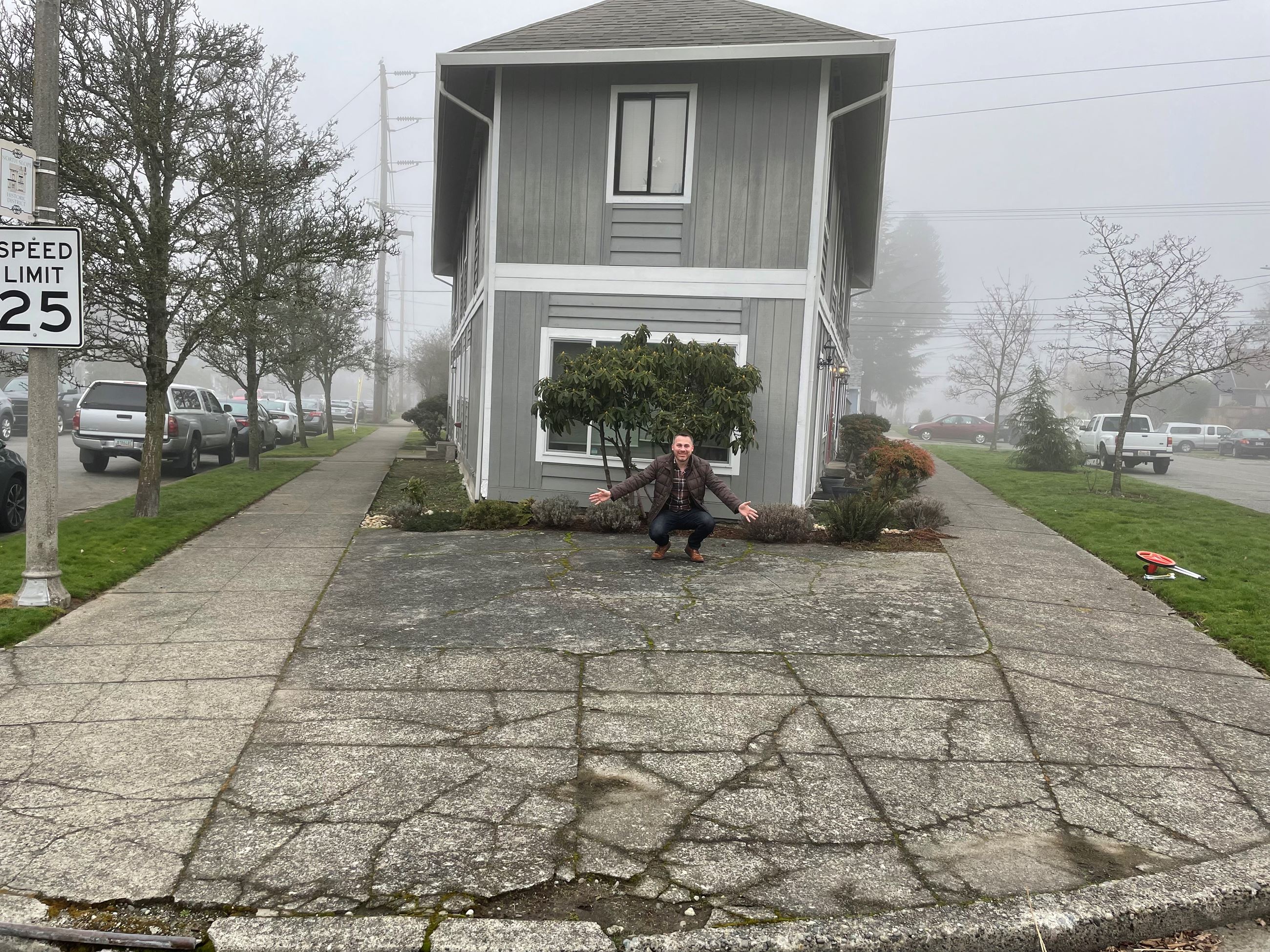 A man stands in front of pavement in front of a house.