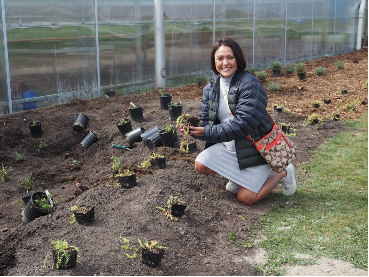 A student plants a tree at the rain garden at Silas High School.