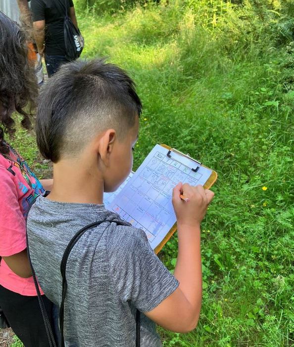 Salishan Eco-Campers work on their nature bingo out in Swan Creek Park.