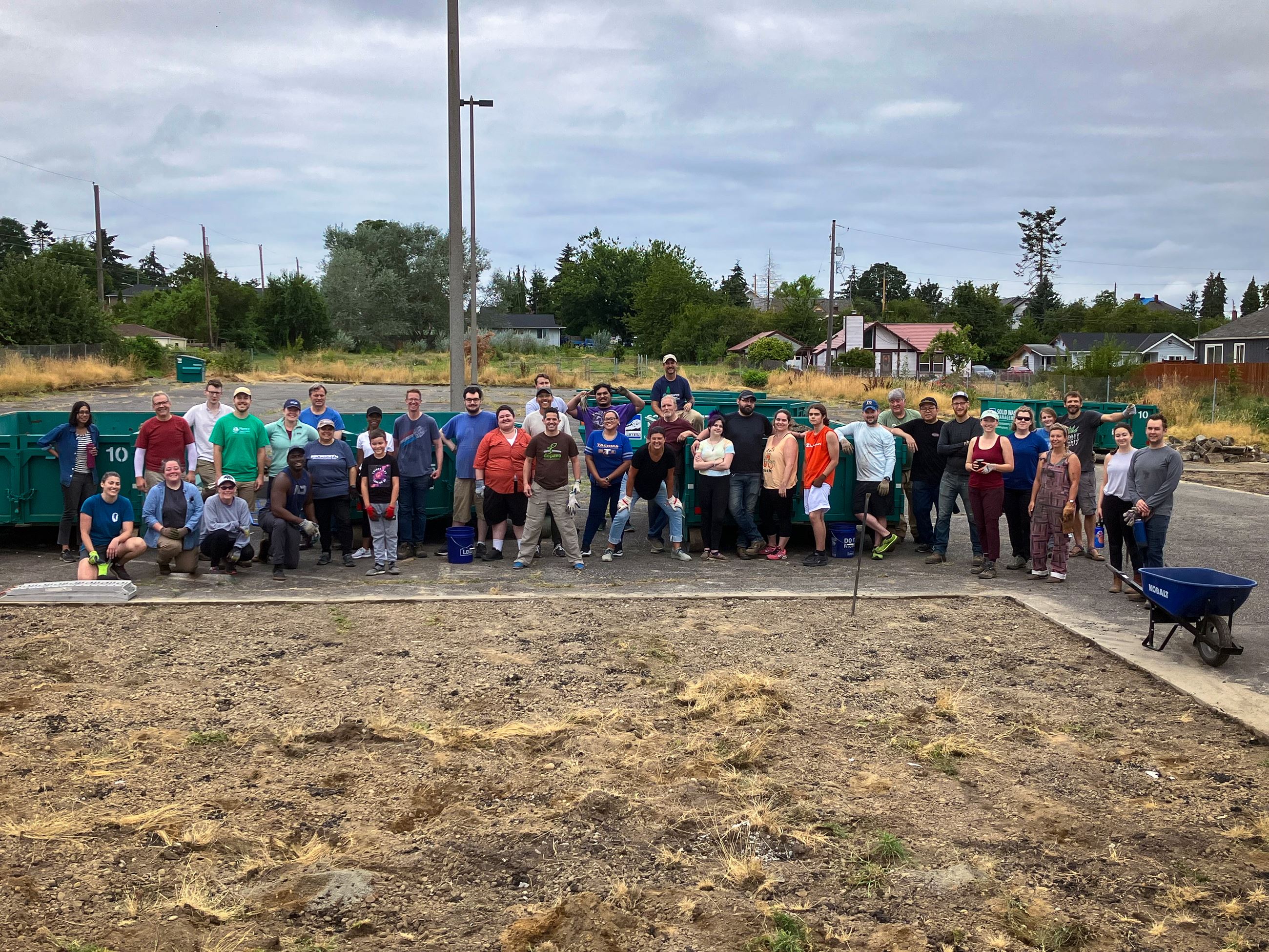 Volunteers standing next to a large area of soil that used to be covered in pavement.