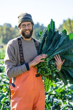 Farmer Rawley Johnson holds a large bundle of freshly harvested kale.