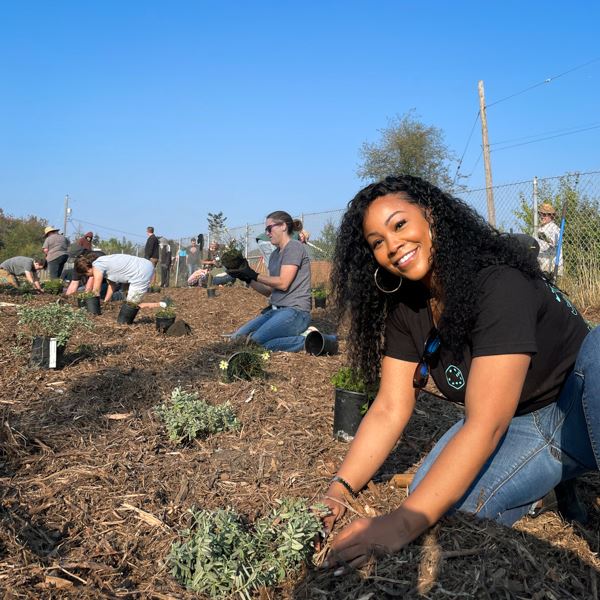 Tacoma City Councilmember Kiara Daniels gets her hands in the soil to plant the new rain garden.