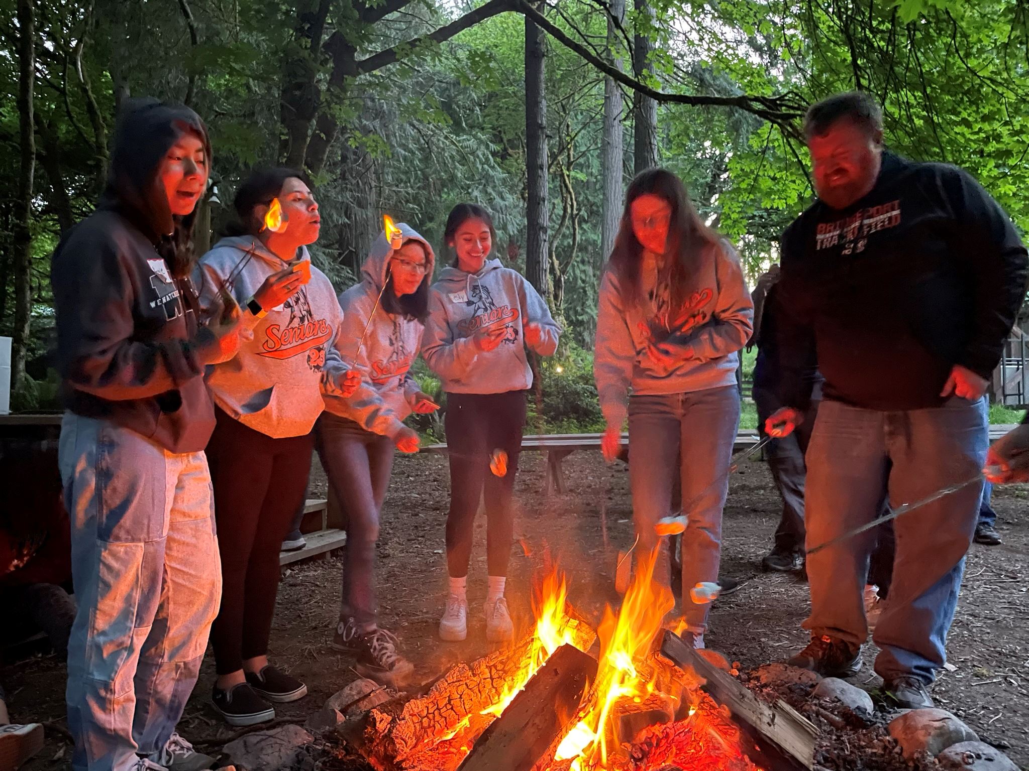 A team roasts marshmallows together over the camp's fire.