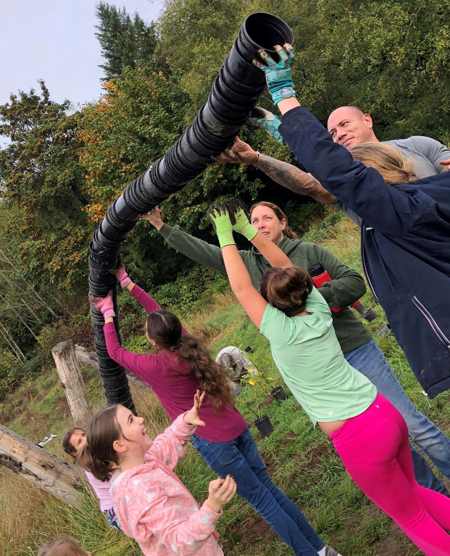 A picture of many volunteers trying to stack a tall tower of plant pots