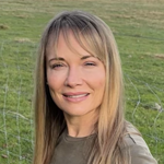 Liz Nicman, Finance Coordinator/HR Assistant, facing forward in front of a grassy background