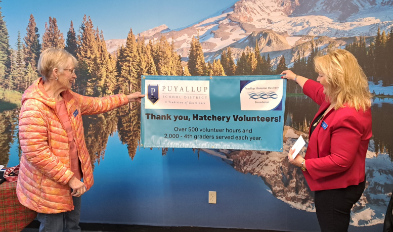 Two volunteers holding up a sign that says "Thank You Hatchery Volunteers!"