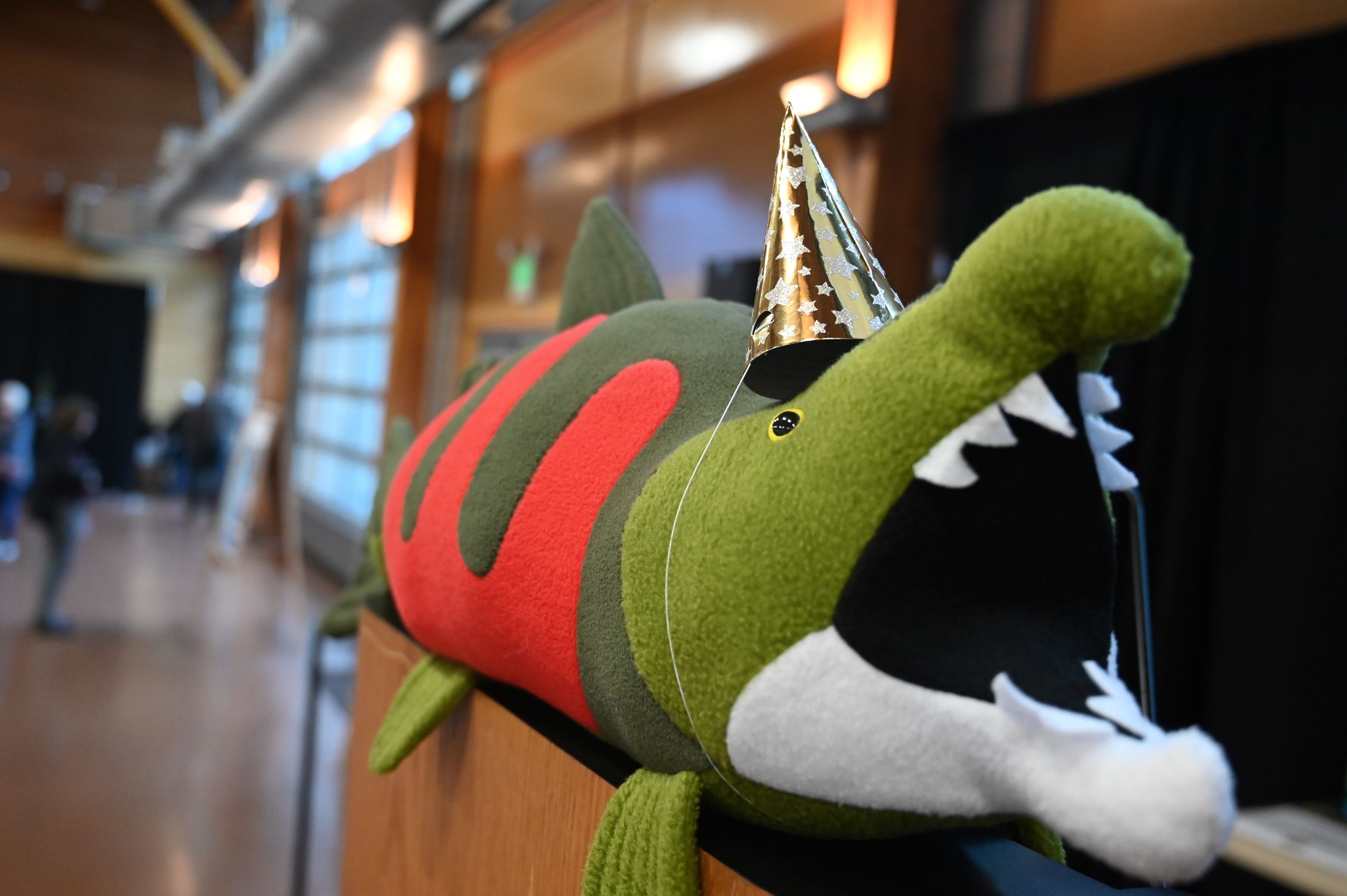 A stuffed salmon with a party hat sitting on a podium.