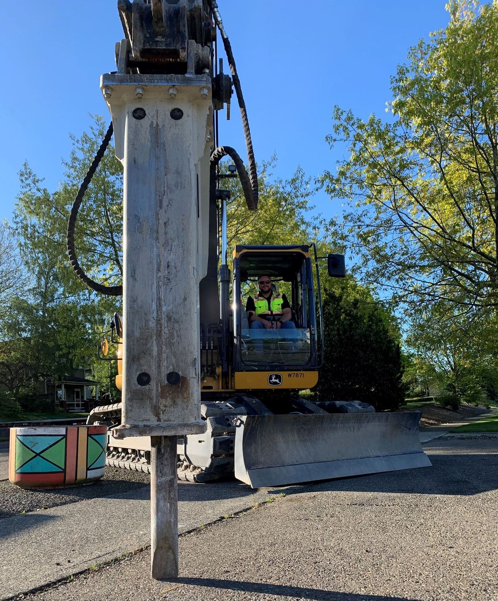 A man sits in the cab of a large jackhammer.