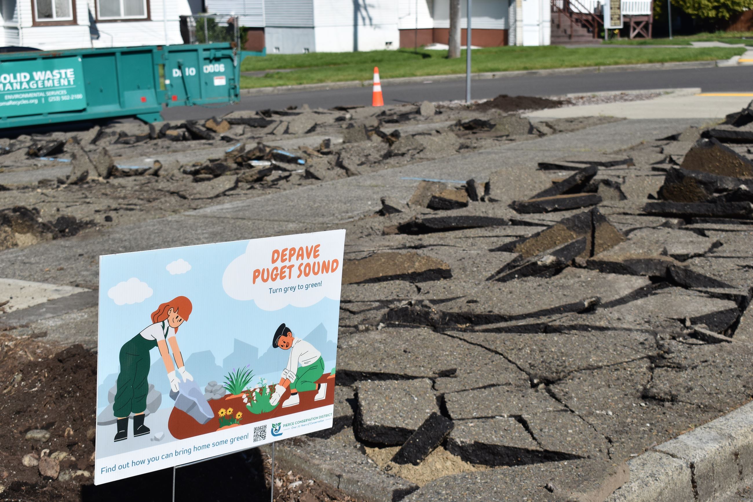 A Depave Puget Sound yard sign in front of broken asphalt.