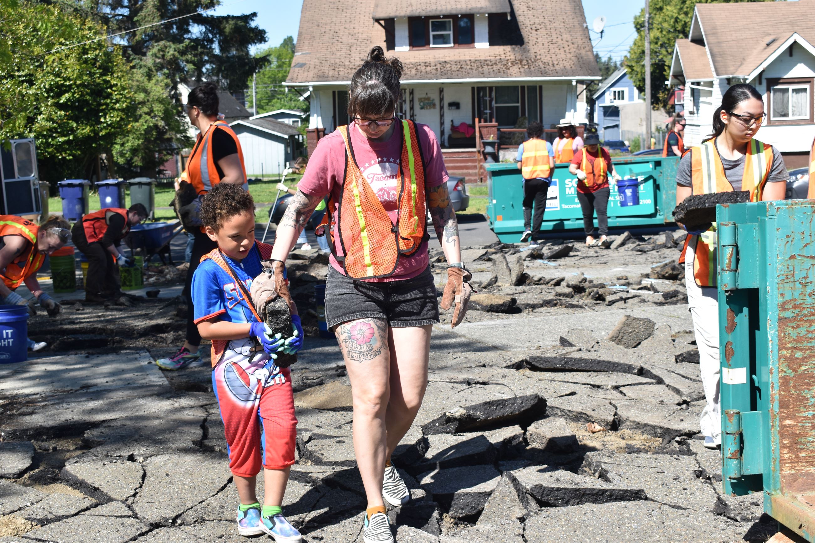 A woman and young boy pick up pieces of asphalt together.