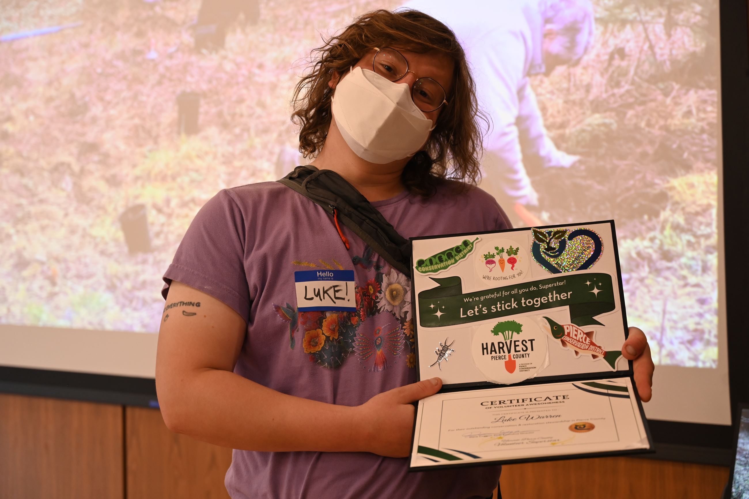 Luke holding the volunteer superstar award and smiling while masked