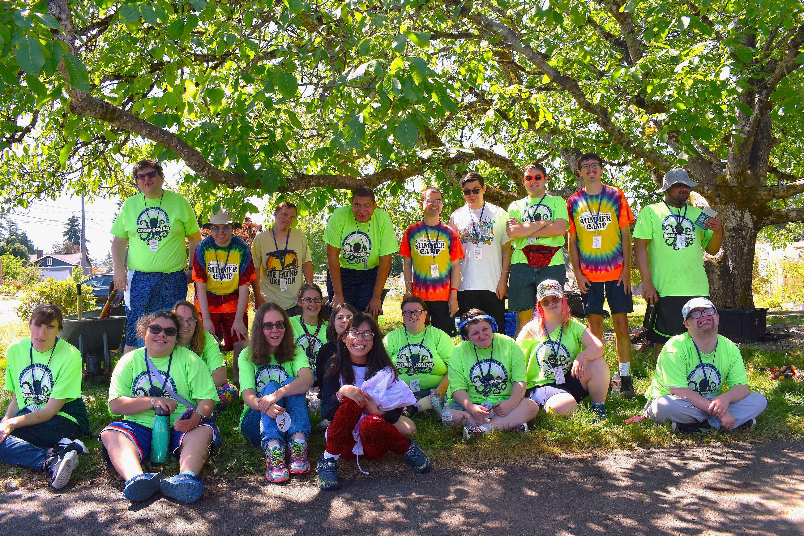 Group of smiling Camp Pierce campers standing and sitting under a large tree.