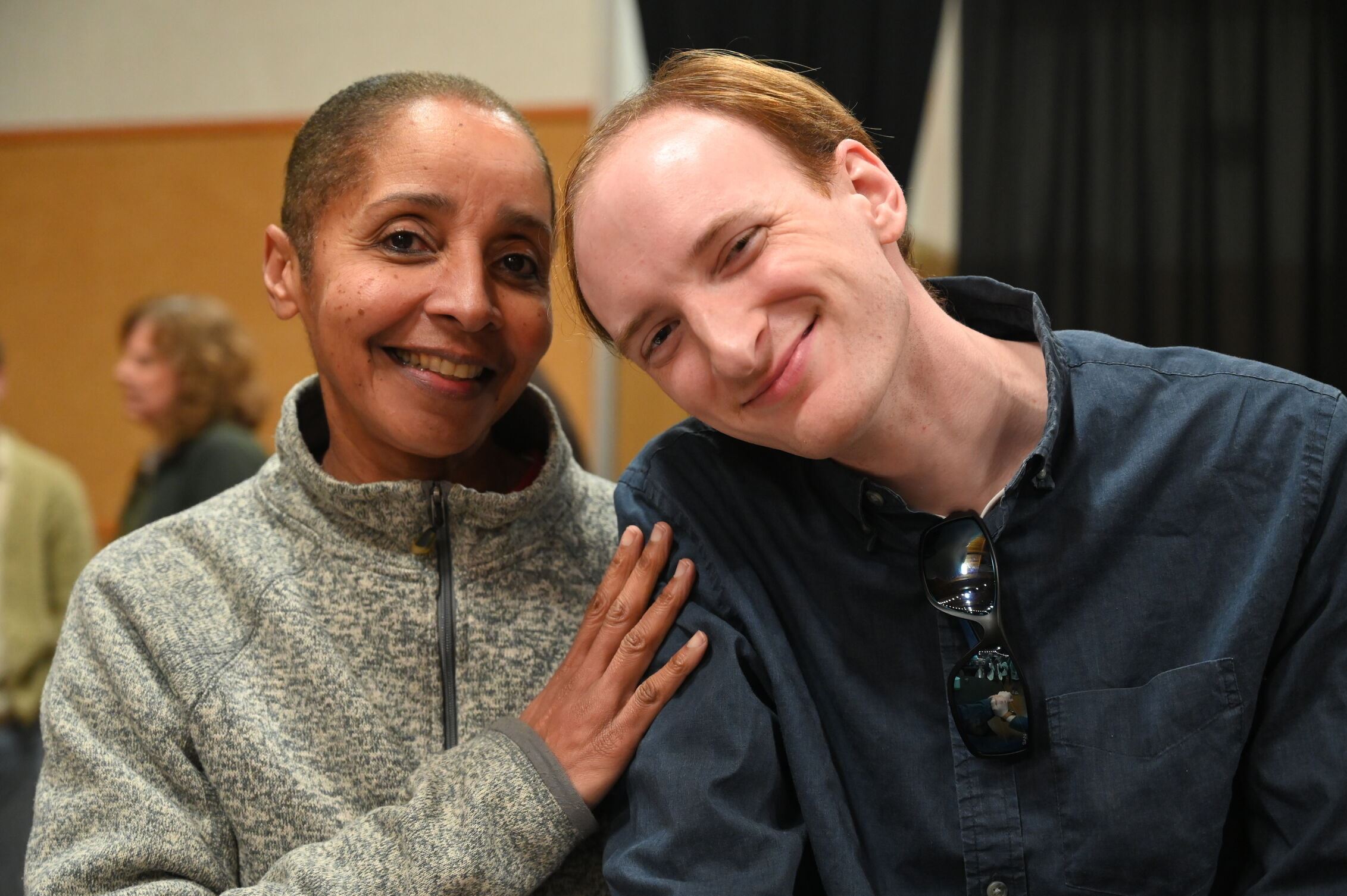A woman rests her hand on a man's shoulder as they smile for a photo together