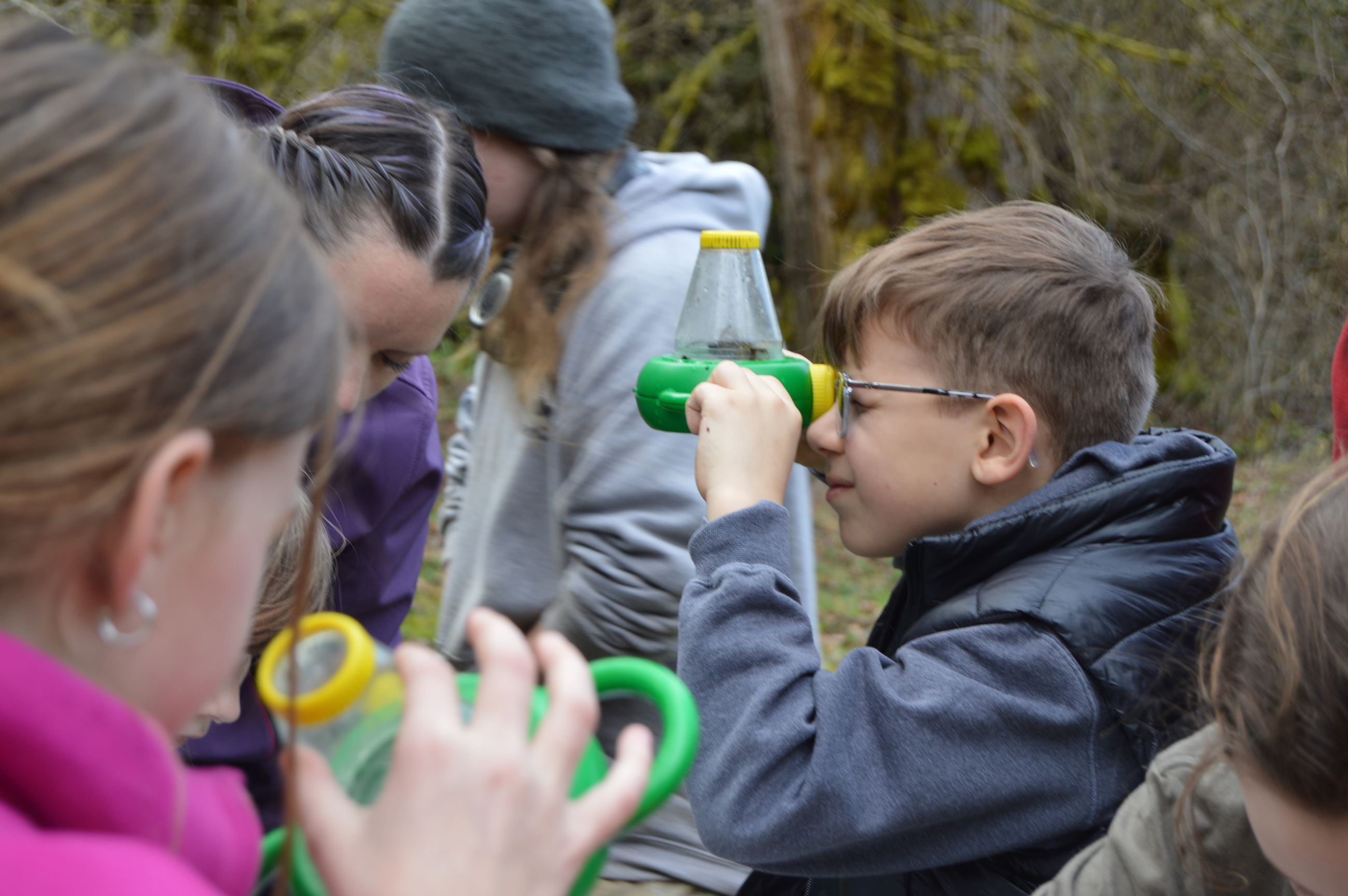 Students use a green viewfinder to look at macroinvertebrates