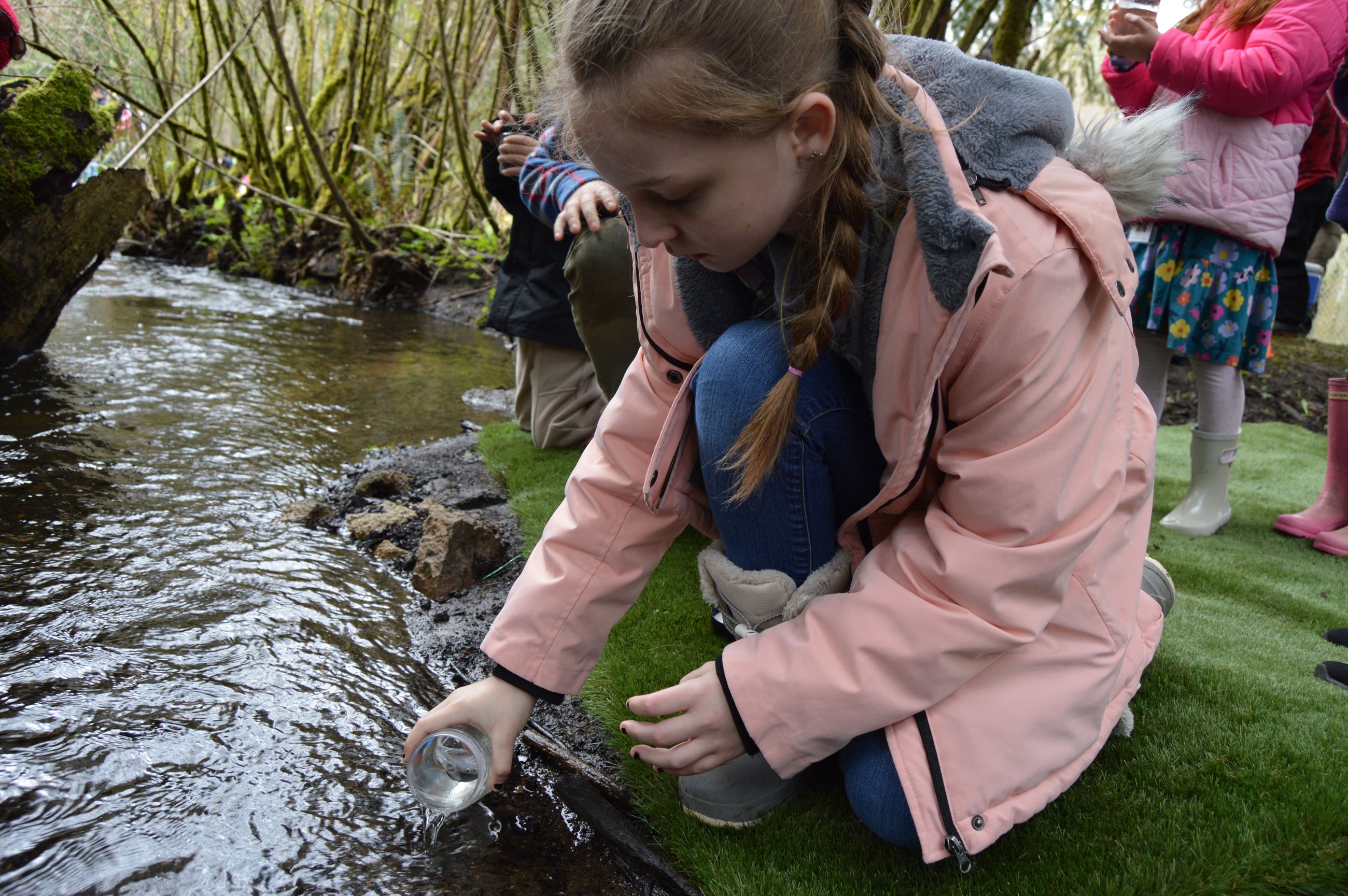 An NCCC AmeriCorps member helps a student release a salmon