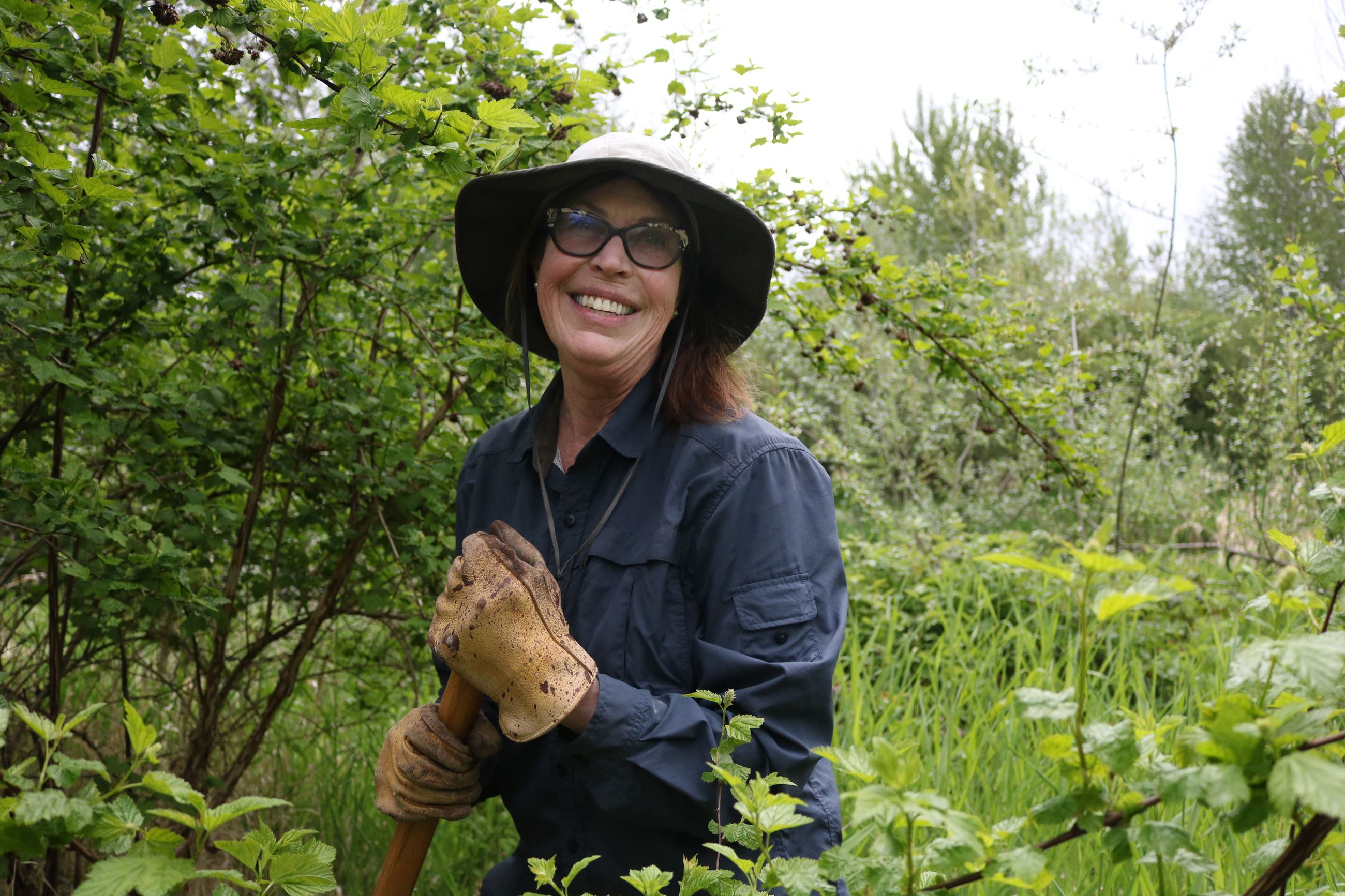 A volunteer smiling with a shovel at Peck Property