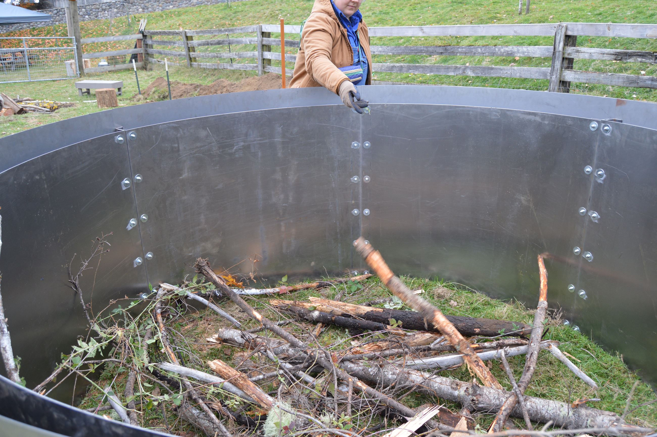 A biochar kiln being filled with sticks and other organic materials.